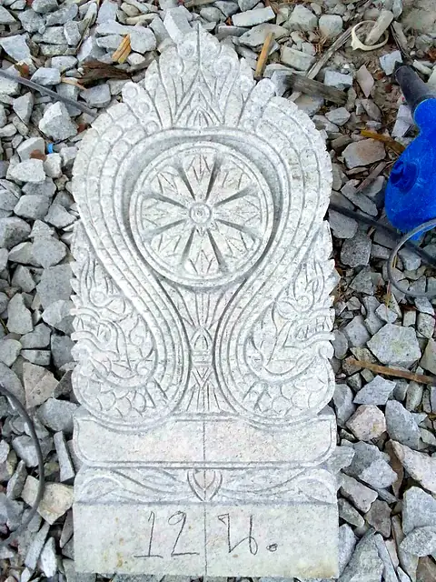 Thai-style headstone with scrollwork and dharma wheel